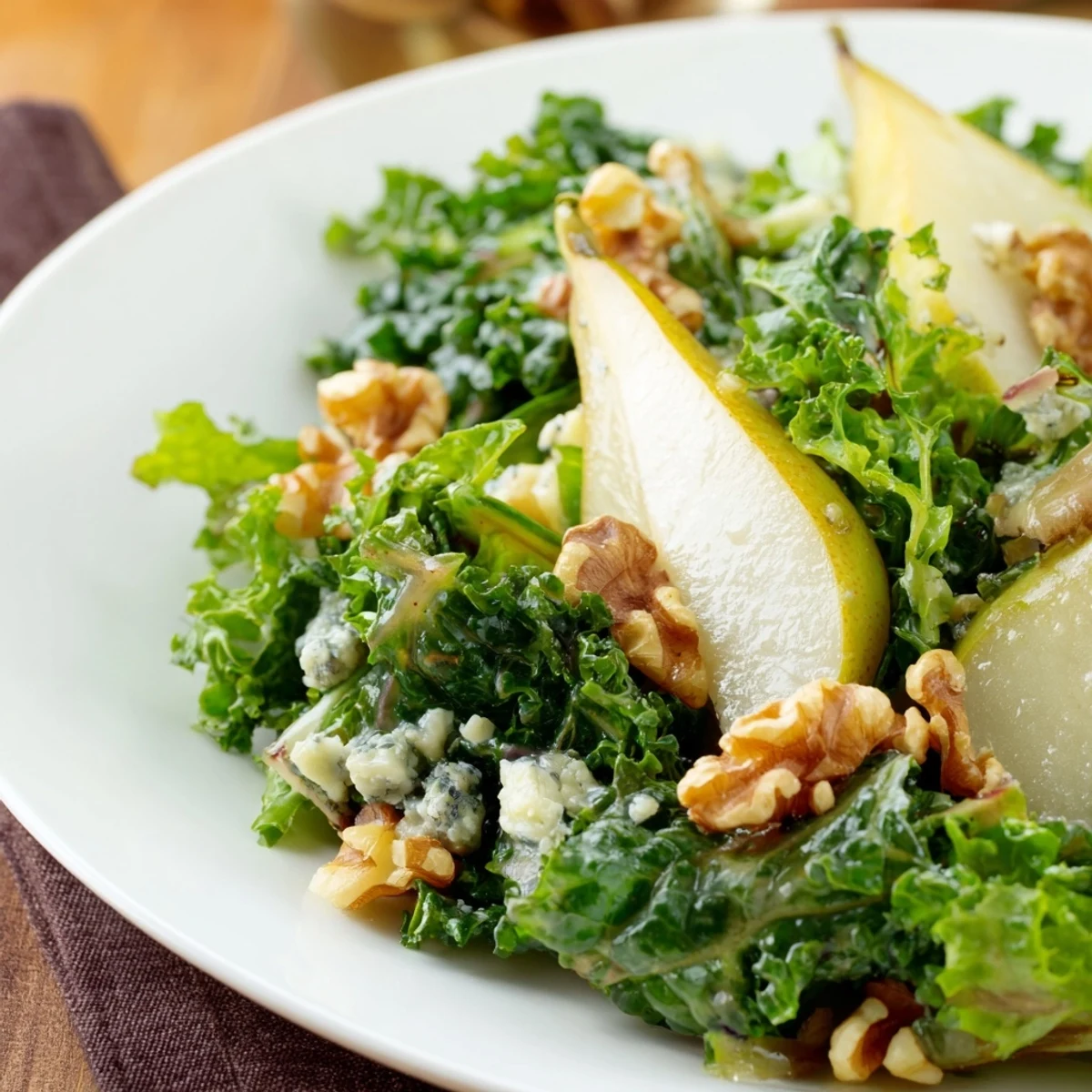 Freshly prepared Winter Green Salad with Pears featuring kale, toasted pecans, and a honey apple cider dressing.