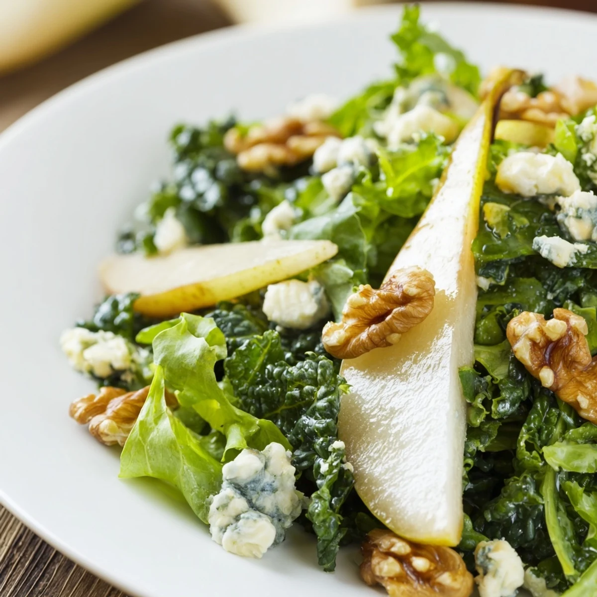 Winter Green Salad with Pears tossed with toasted walnuts and creamy goat cheese on a rustic table.