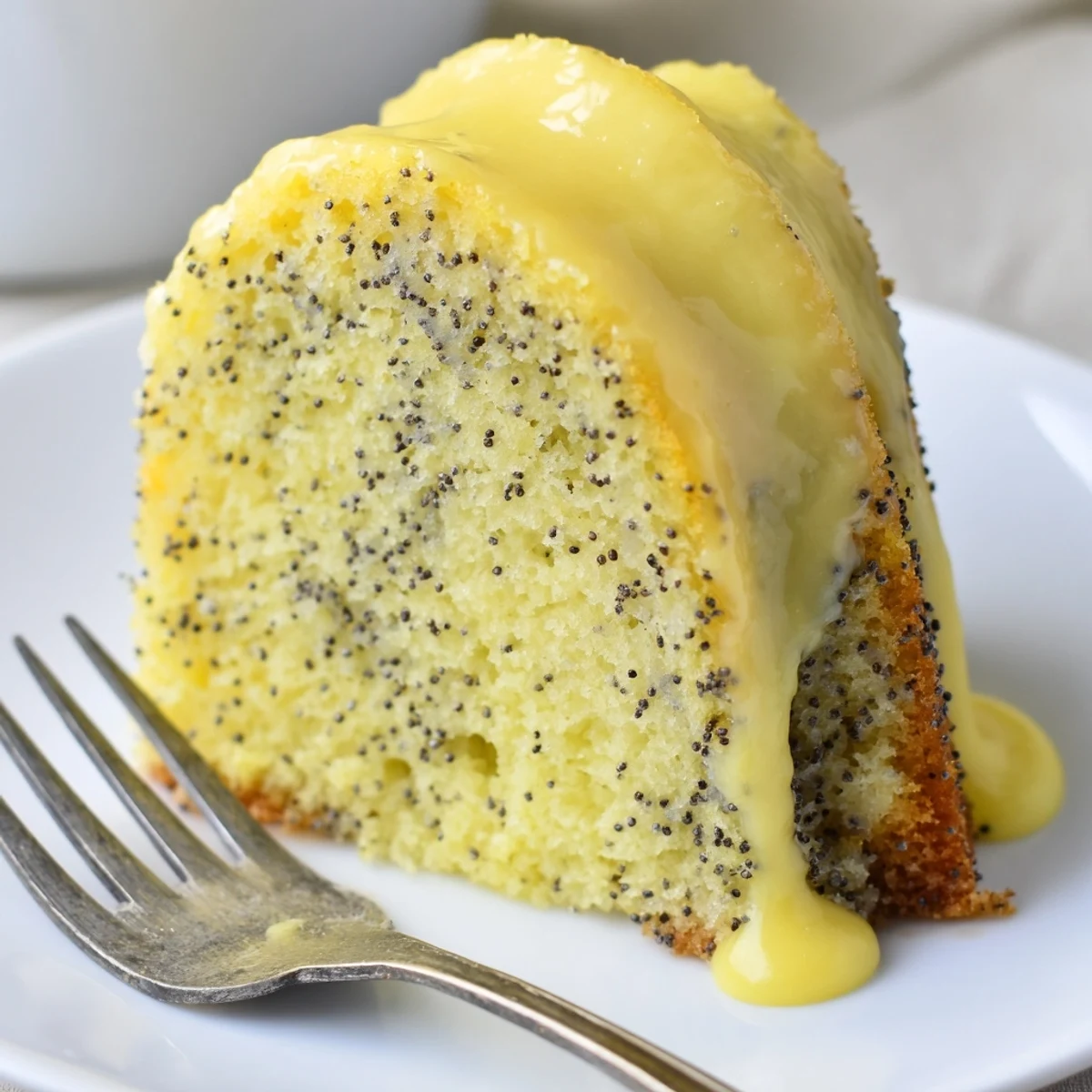 Freshly glazed Lemon Poppy Seed Bundt Cake with a zesty lemon drip on a cooling rack.