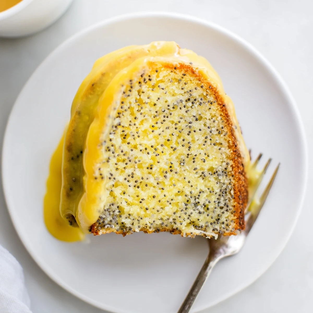 Whole Lemon Poppy Seed Bundt Cake with golden crust and tangy glaze, ready to slice.