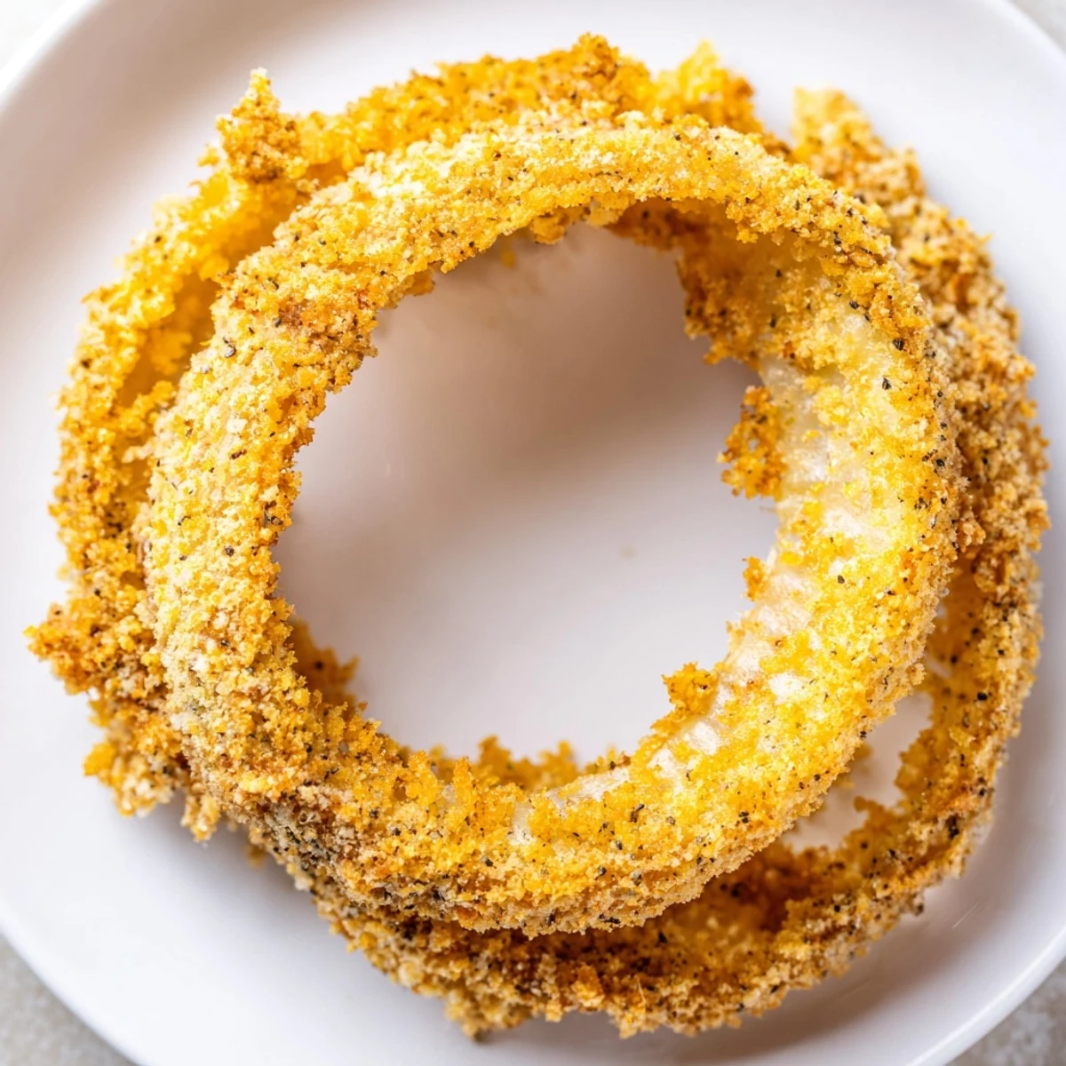Homemade crispy baked onion rings cooling on a wire rack, showing a crunchy panko and Parmesan crust.