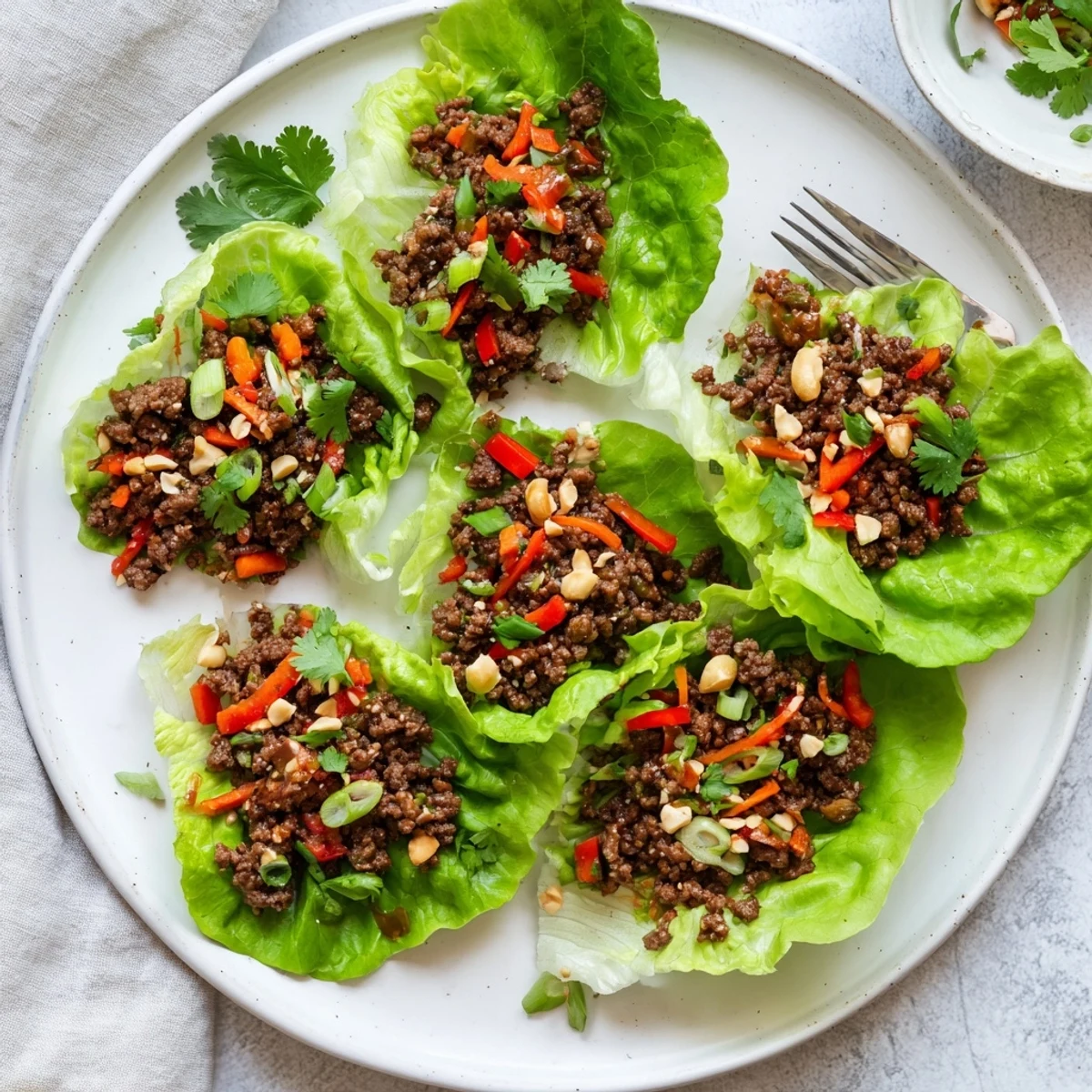 Vivid, sizzling ground beef with crisp vegetables and tangy hoisin sauce nestled in fresh, tender lettuce cups ready to enjoy.
