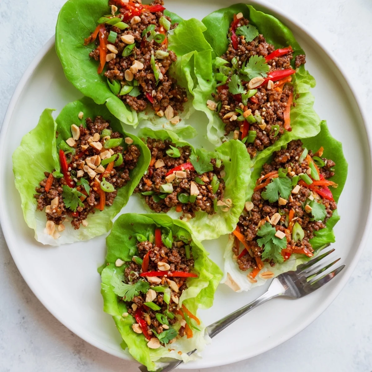 Golden-brown beef filling mingling with diced onion, bell pepper, and carrot in a glossy hoisin glaze, served in chilled lettuce wraps.
