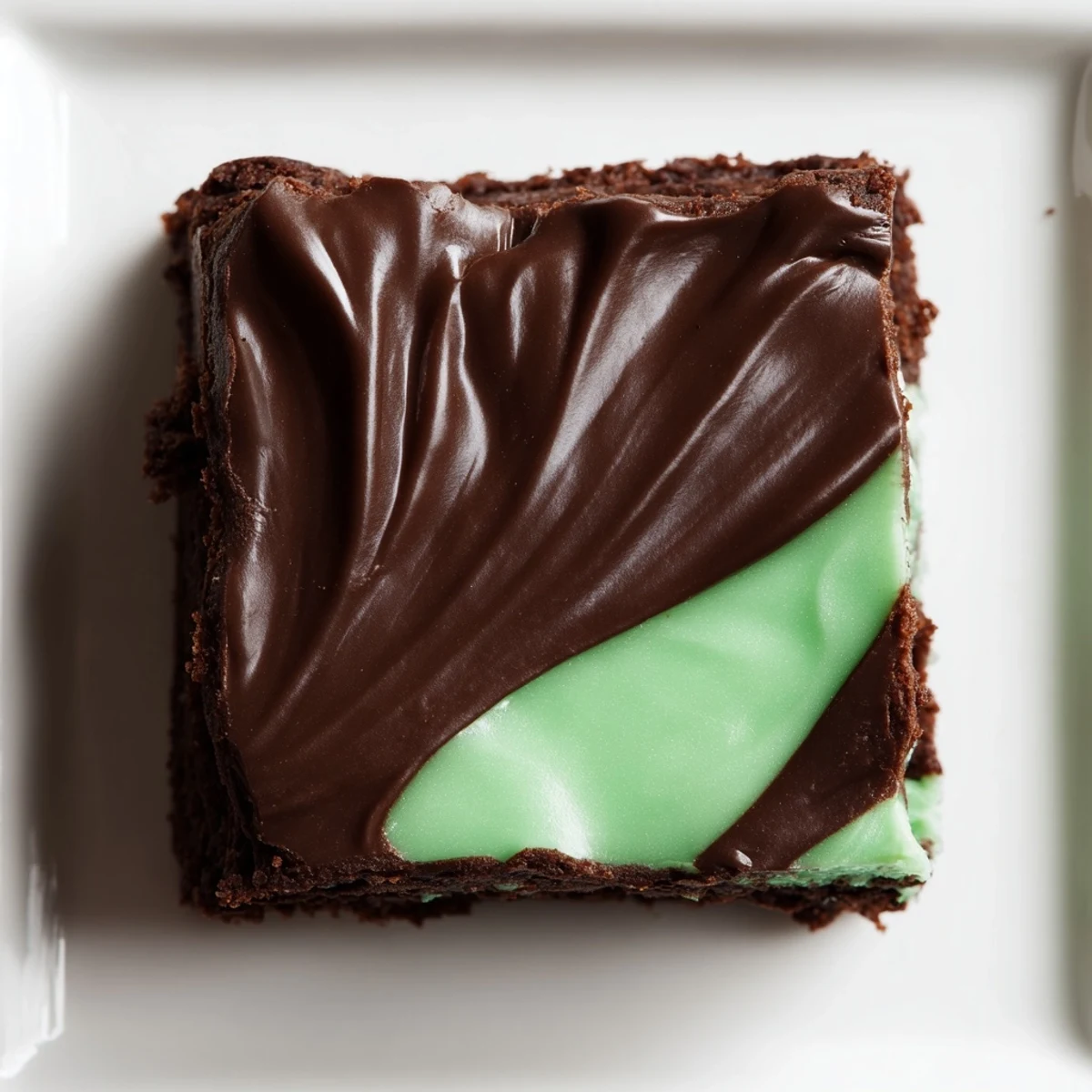 Lush green mint brownies with a fudgy texture, topped with glossy chocolate glaze and cut into neat squares. 