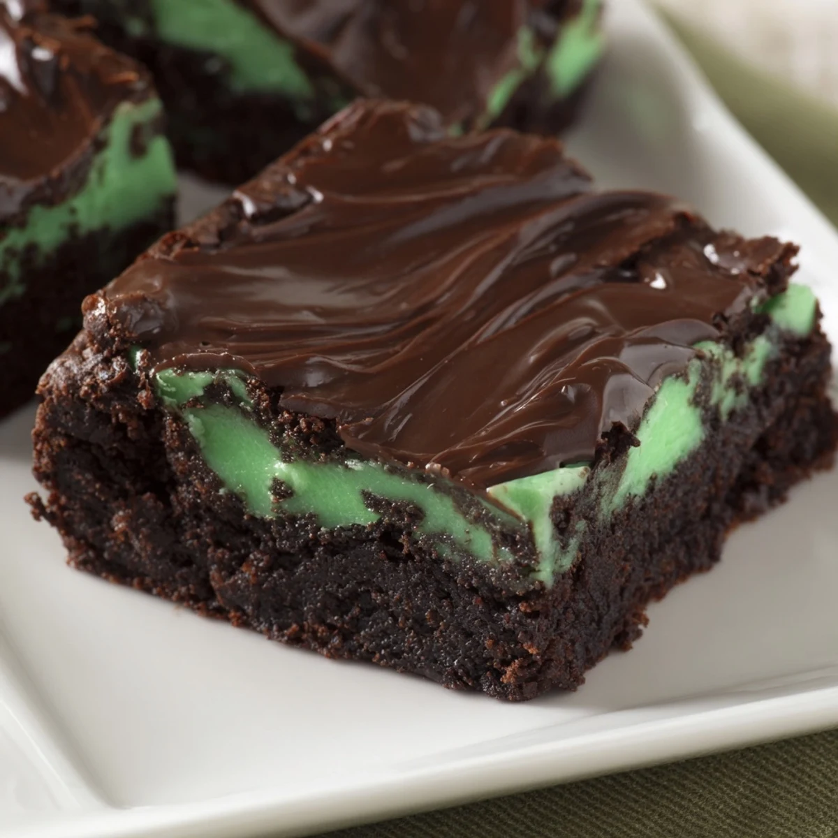 Close-up shot of a mint brownie square, highlighting moist texture and rich chocolate topping for dessert lovers.