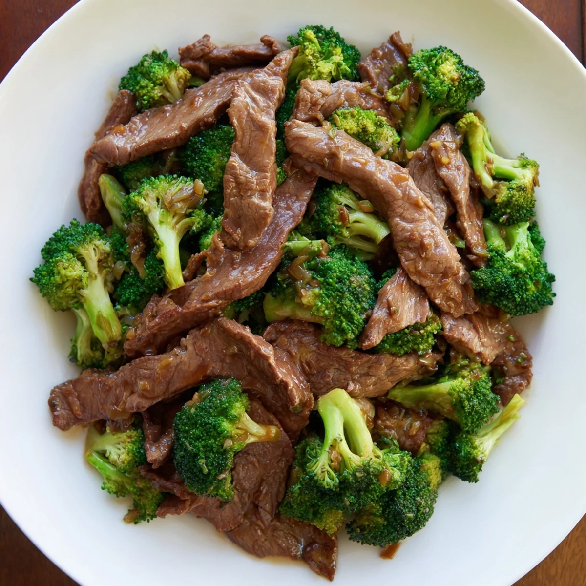 Steaming Beef and Broccoli with Soy Sauce tossed in a savory glaze, served over white rice in a white bowl with chopsticks.