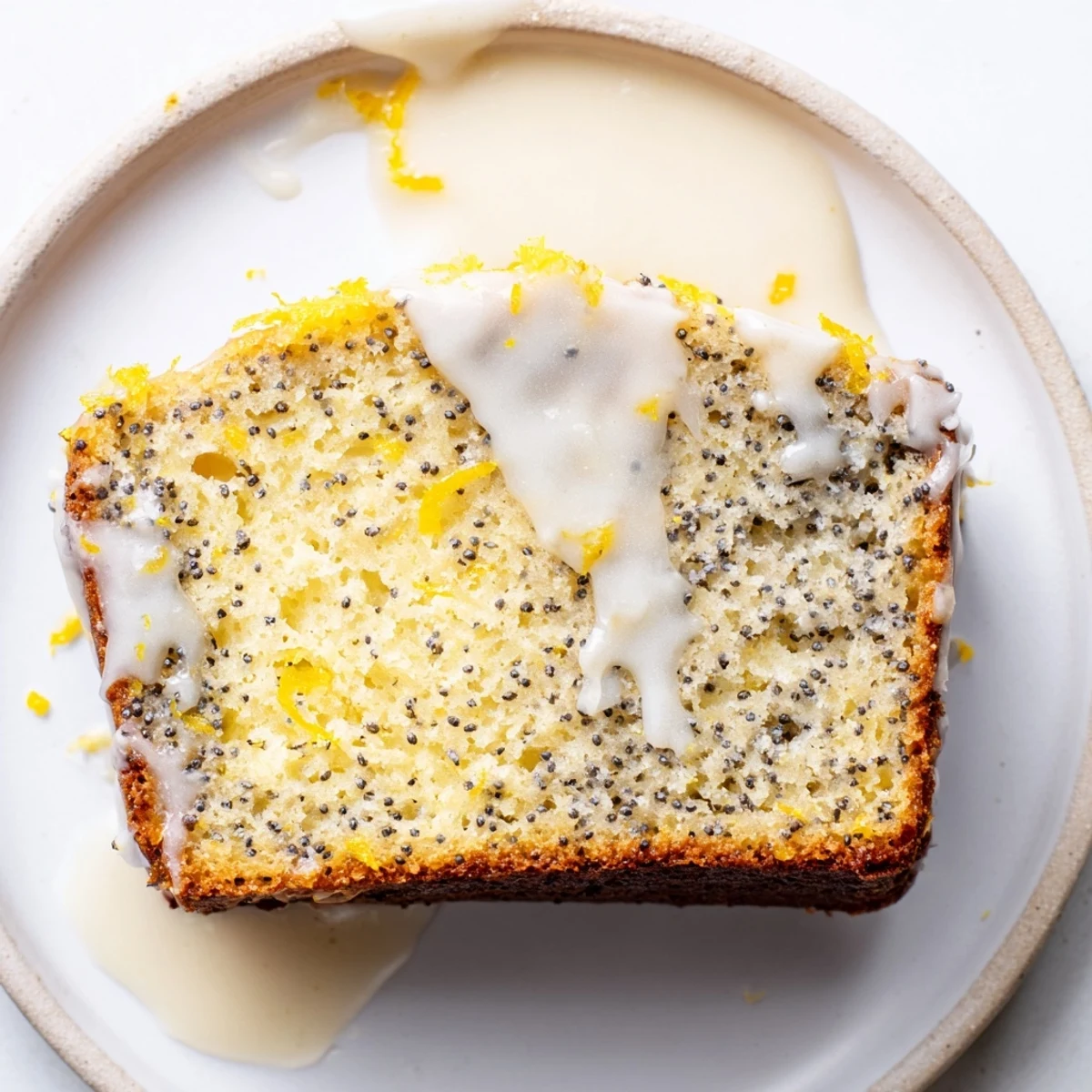 Moist Lemon Poppy Seed Loaf with visible poppy seeds and a thick lemon glaze, ready to slice for breakfast.