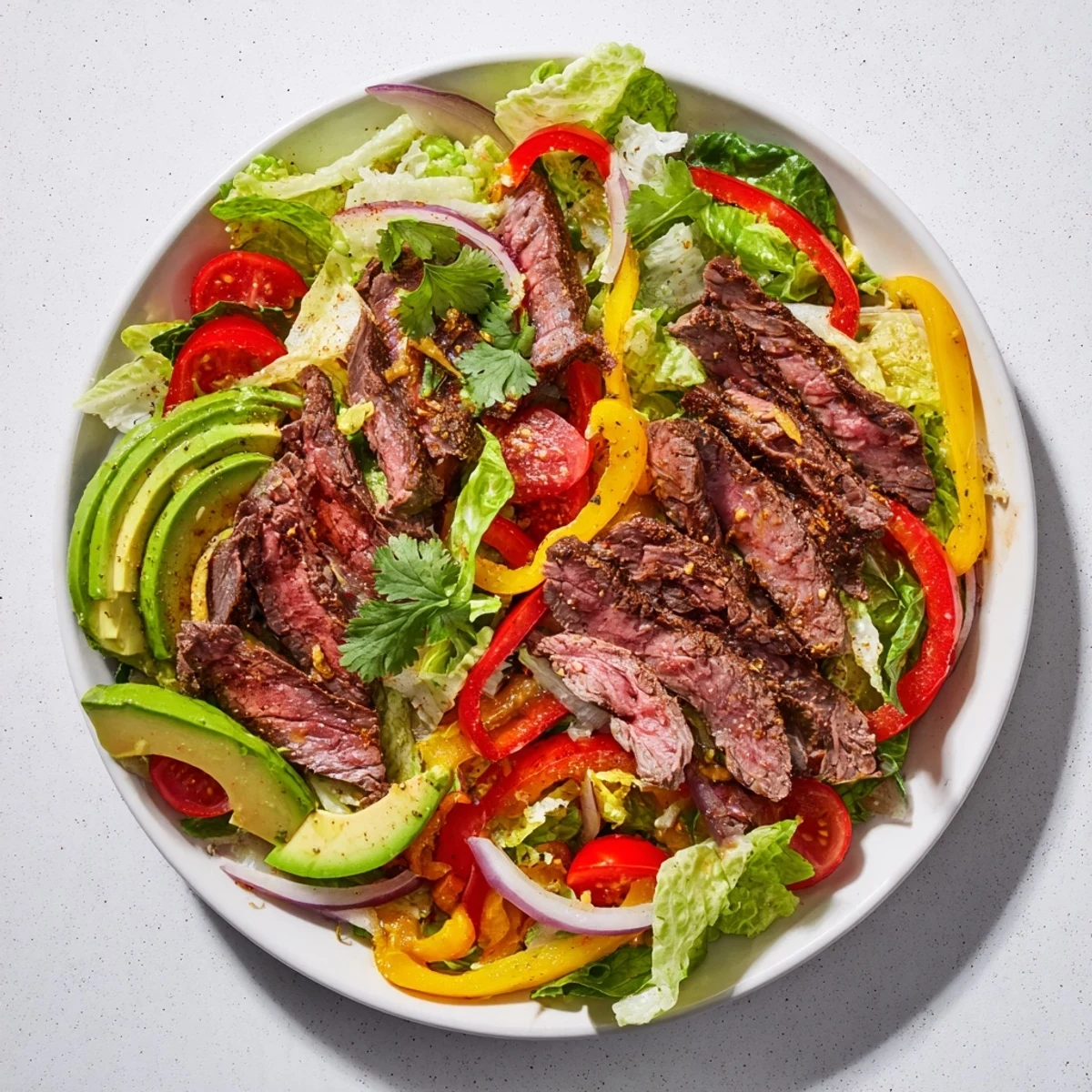 Tender strips of spiced beef sizzling on a skillet next to crisp romaine and bright peppers for Beef Fajita Salad.