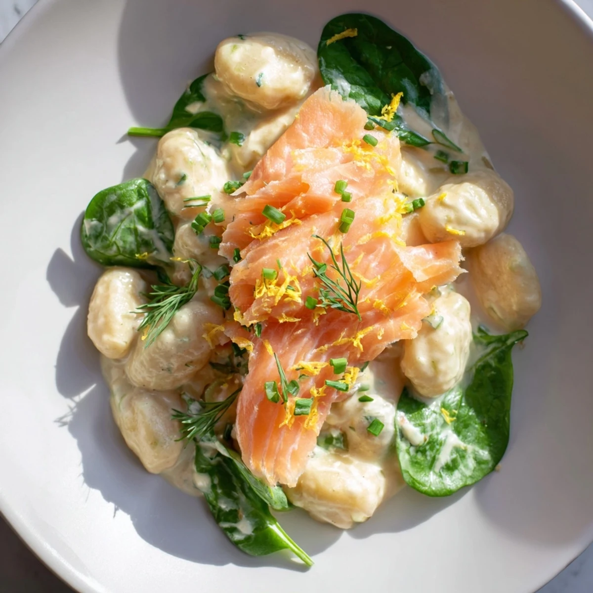 Creamy Healthy Smoked Salmon Gnocchi with dill and fresh spinach in a skillet.