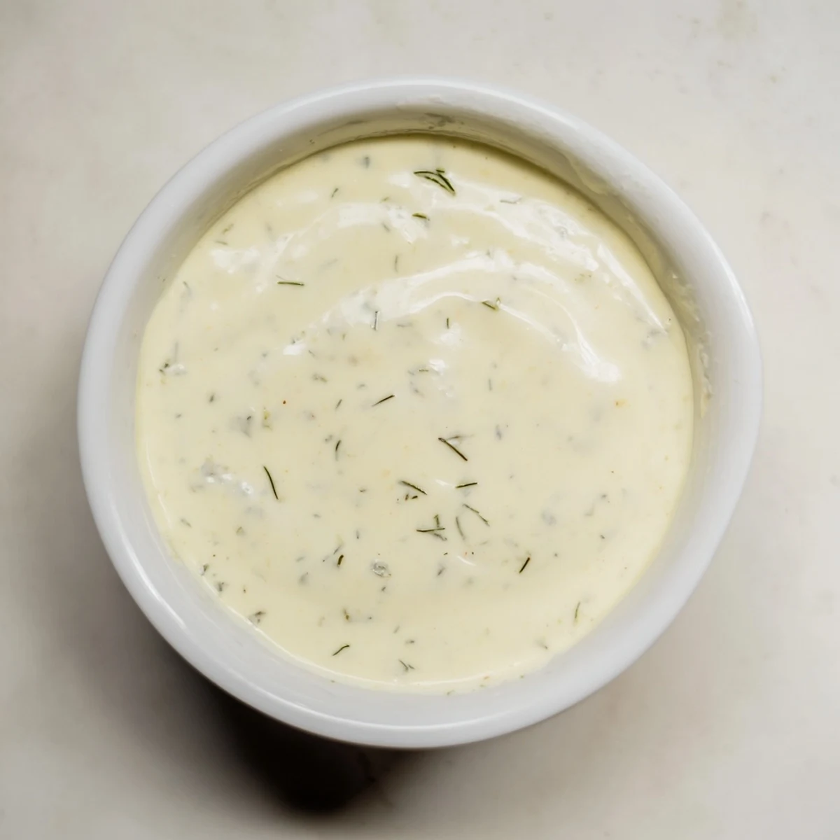 Homemade Hot Honey Ranch Crispy Chicken Tenders Sauce drizzled over a plate of fried chicken and fresh herbs.