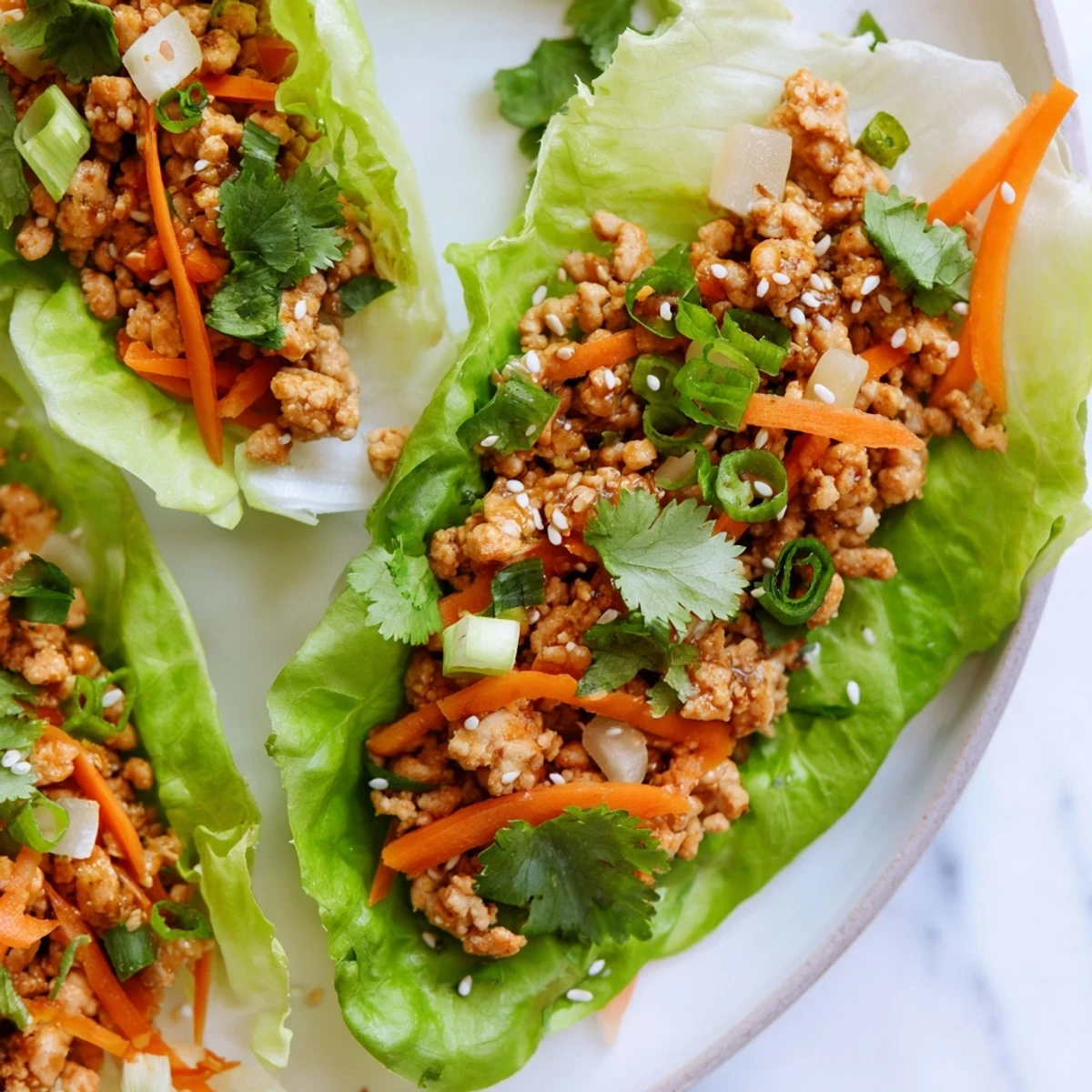 Freshly cooked ground chicken with ginger and garlic rests in crisp butter lettuce cups, finished with toasted sesame seeds for a Potsticker Chicken Lettuce Boats recipe.  