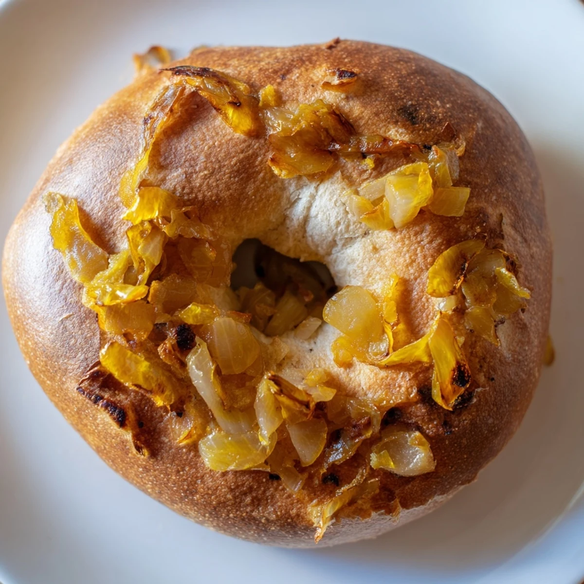 Freshly baked sourdough onion bagels with golden crust and caramelized onion topping on a wooden board.