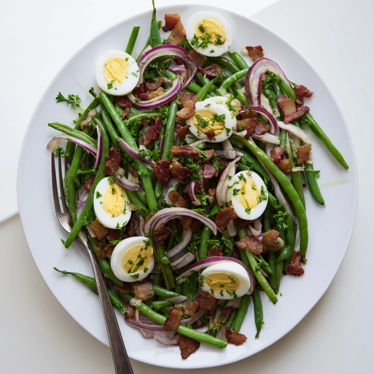 A close-up of Green Bean, Bacon, and Egg Salad with bright green beans and crispy bacon bits on a rustic plate.