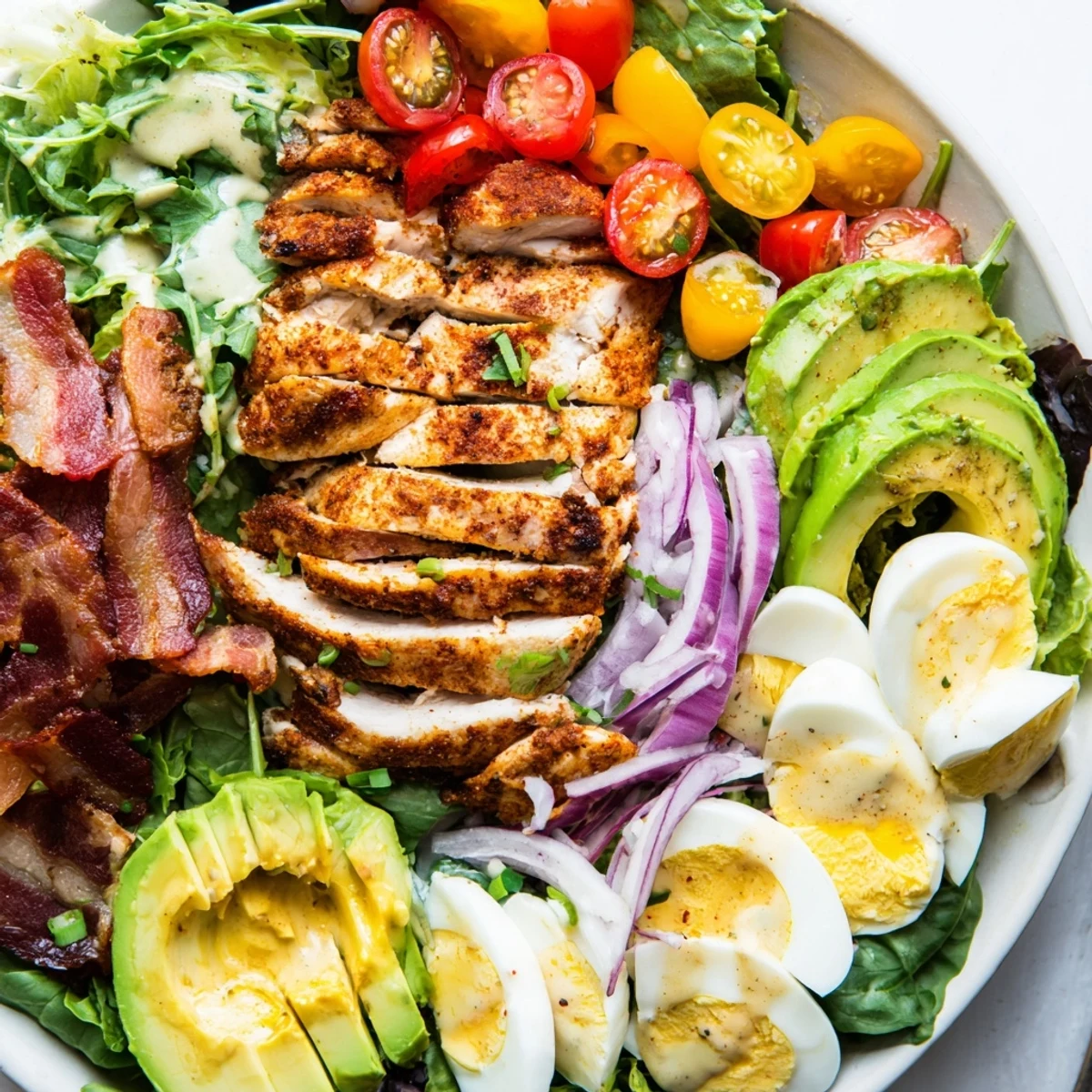 Drizzling tangy honey Dijon dressing over the vibrant Paleo Grilled Chicken Cobb Salad With Smoky Bacon and grilled chicken for a gluten-free meal.