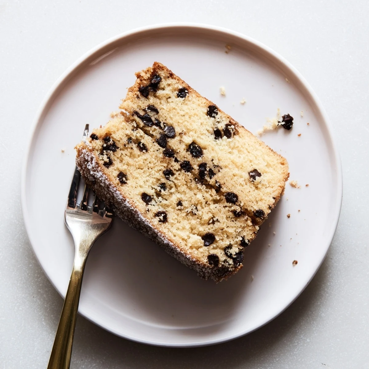 Close-up of Chocolate Chip Cake batter folded with semi-sweet chips in a glass bowl, with flour-dusted chocolate pieces ready to bake.