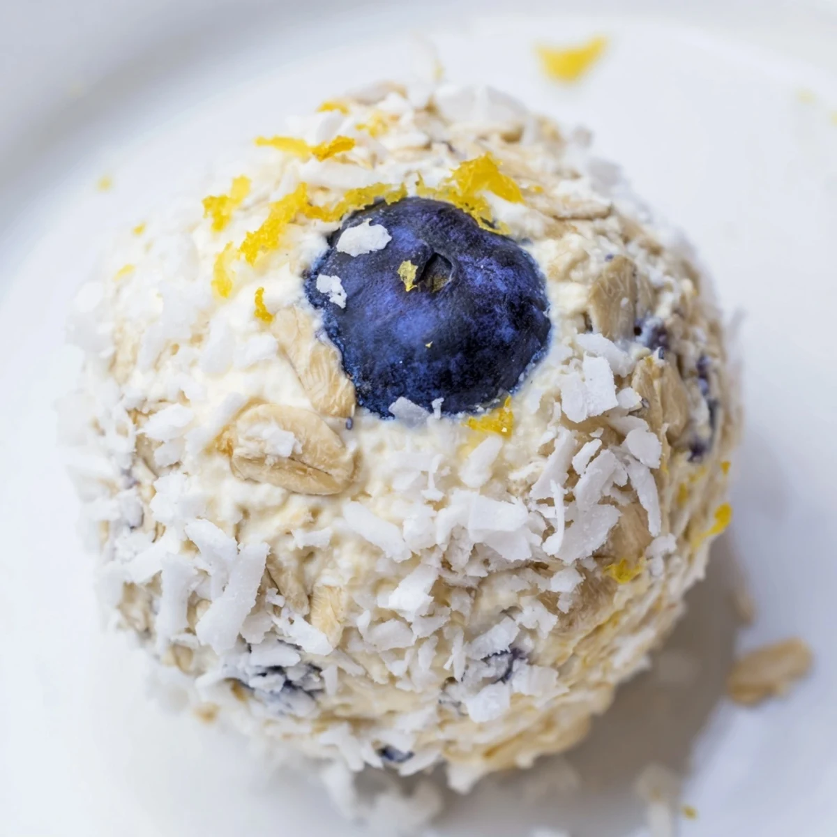 A plate of Lemon Blueberry Cottage Cheese Protein Bites with a lemon wedge garnish, embodying a refreshing and energizing no-bake bite for busy mornings.