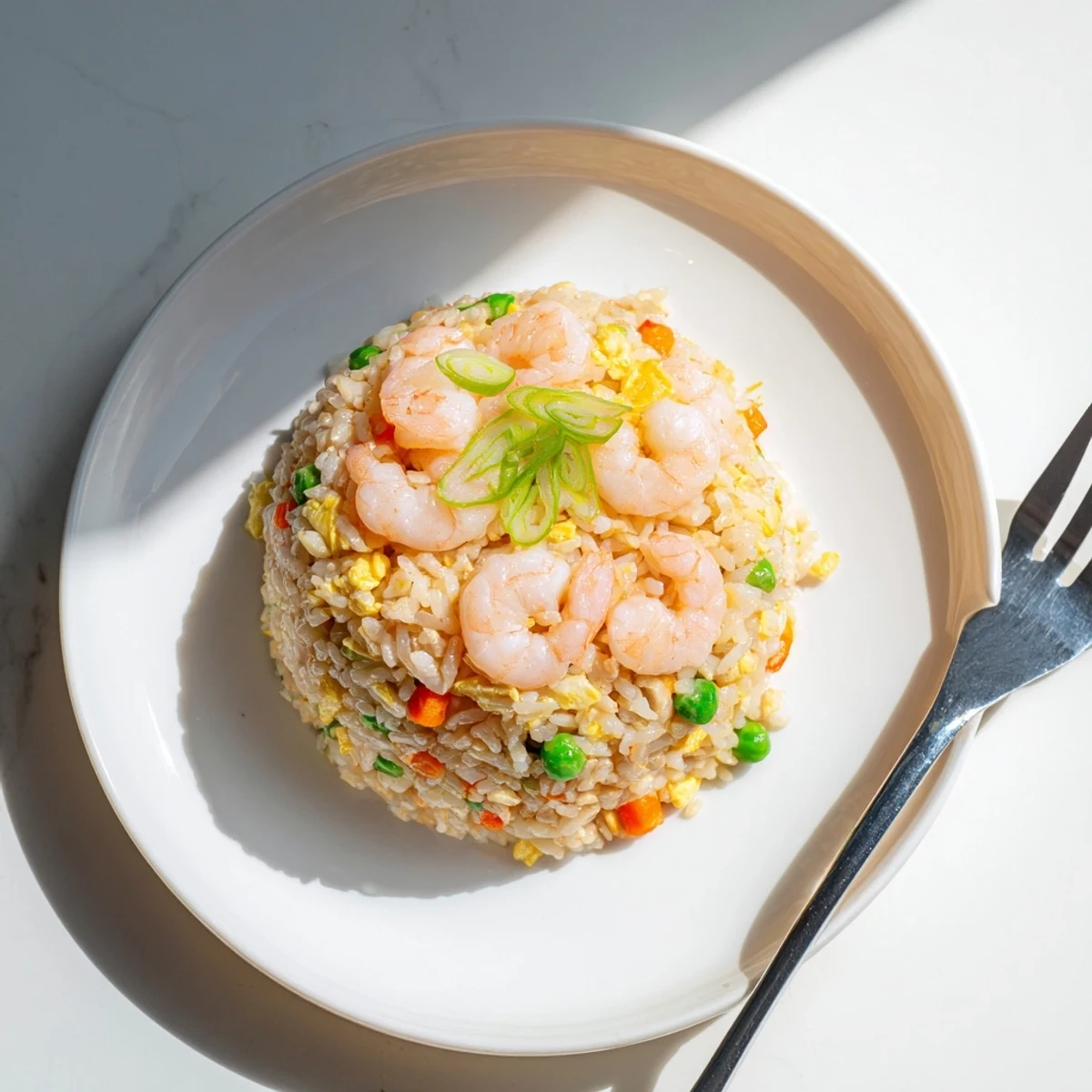 Golden shrimp fried rice with colorful peas and carrots served in a white bowl