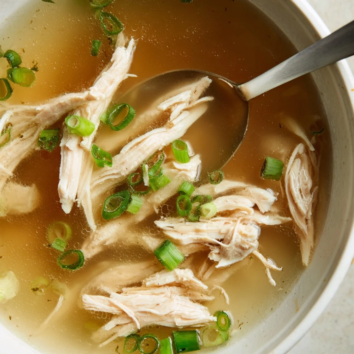 Steaming Dakgomtang featuring tender shredded chicken in clear broth with sesame garnish