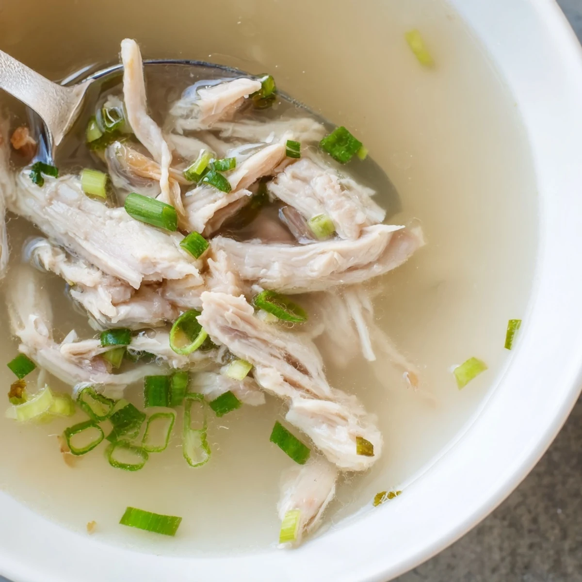 Golden bowl of Dakgomtang Korean chicken soup topped with fresh green onions