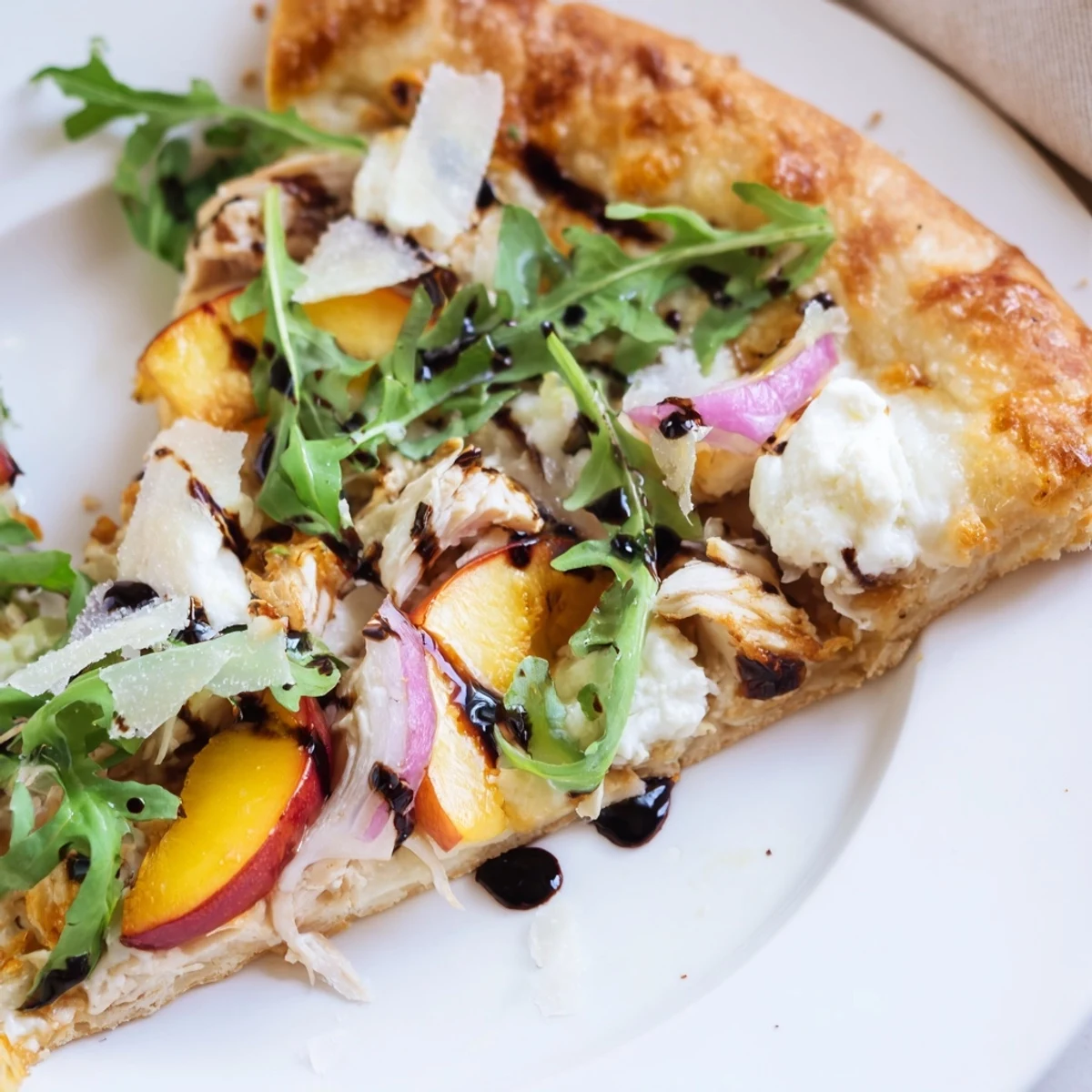 Summer chicken peach ricotta pizza with peppery arugula on bubbling mozzarella crust