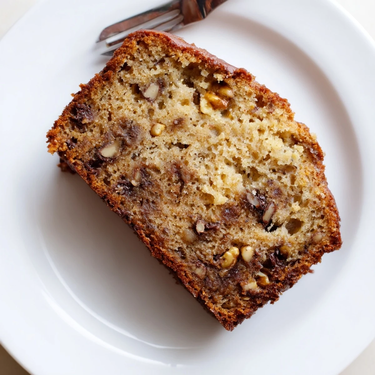 Slice of moist banana bread made with sour cream showing soft interior and golden crust