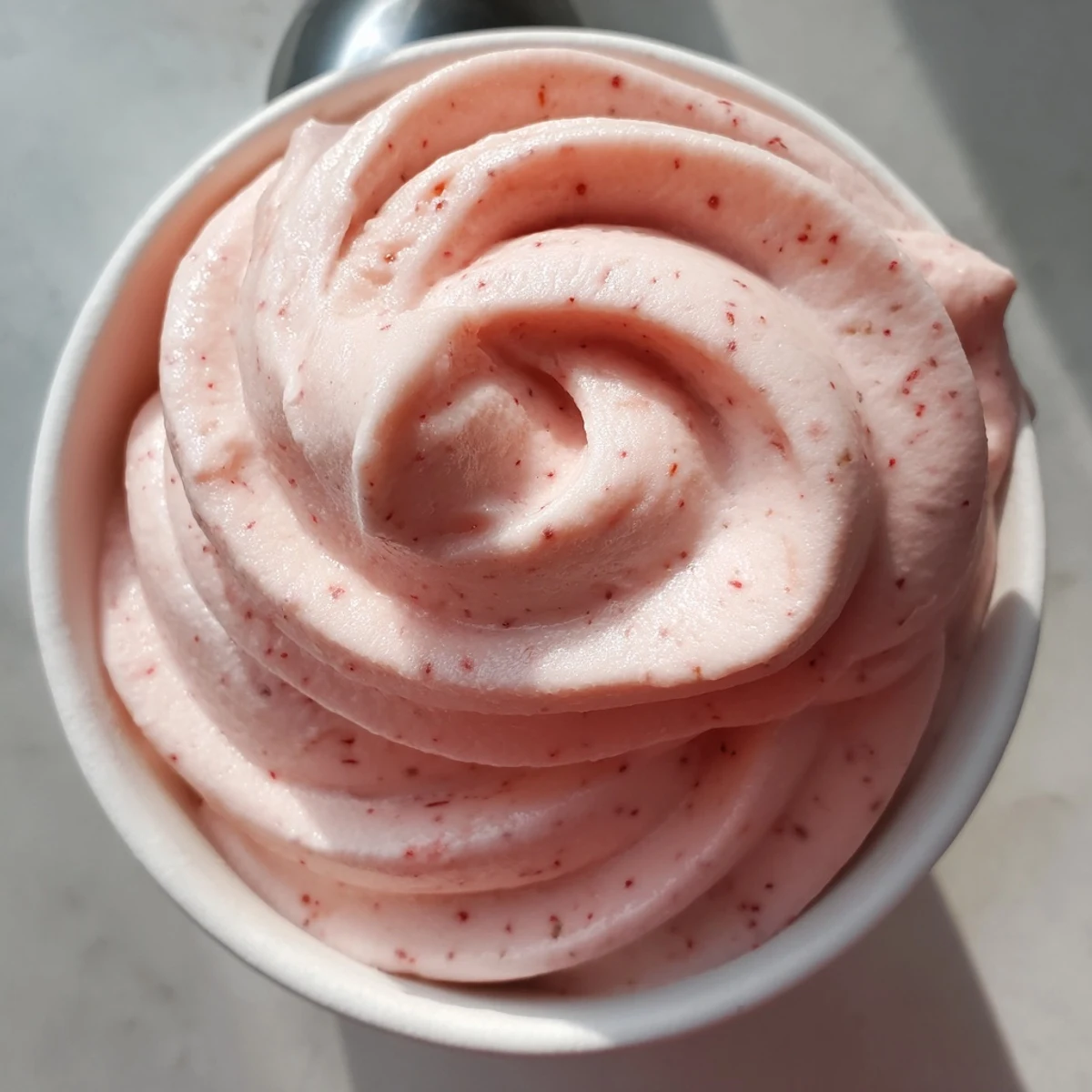Vegan strawberry Dole Whip delight scooped into a bowl with toasted coconut garnish