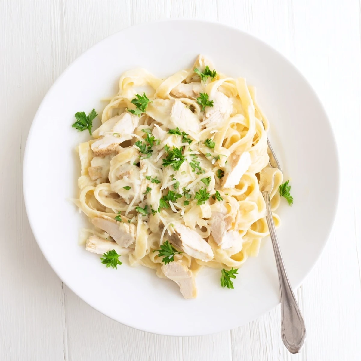 Creamy garlic Parmesan chicken pasta tossed in a rich white cheese sauce with sliced chicken breast and fresh parsley garnish