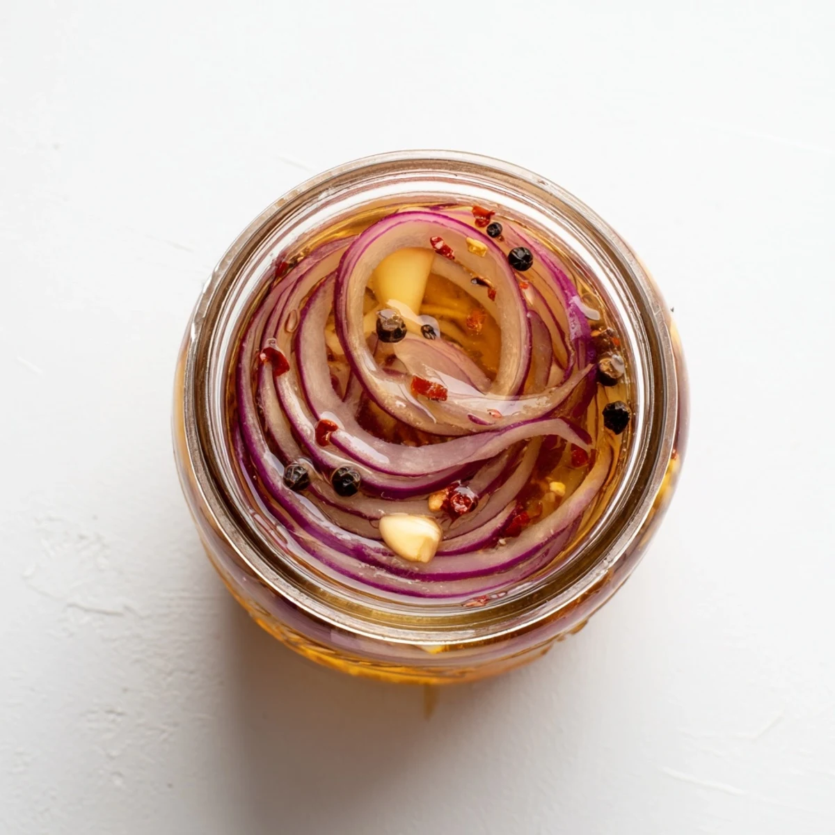 Mason jar showcasing thinly sliced red onions pickled in sweet and spicy hot honey mixture