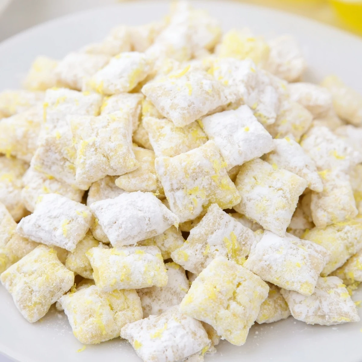 Sweet and tangy lemonade puppy chow piled high on a white serving platter