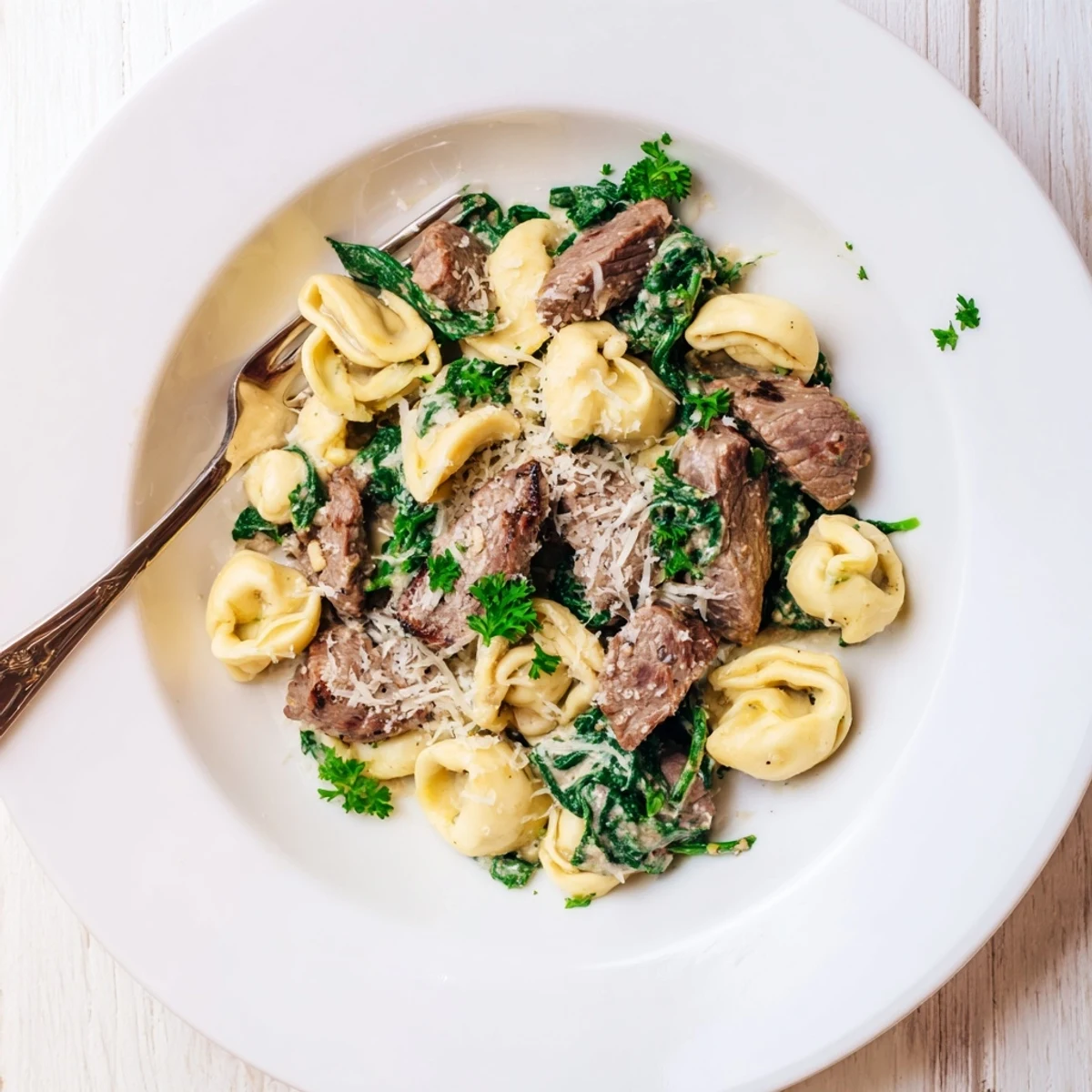 Plate of garlic steak tortellini garnished with fresh parsley and extra parmesan cheese