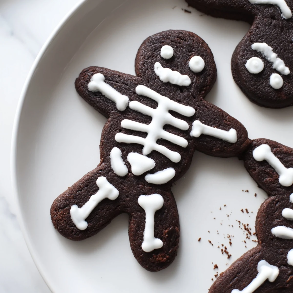 Dark cocoa chocolate cinnamon skeleton cookies decorated with intricate royal icing bone designs