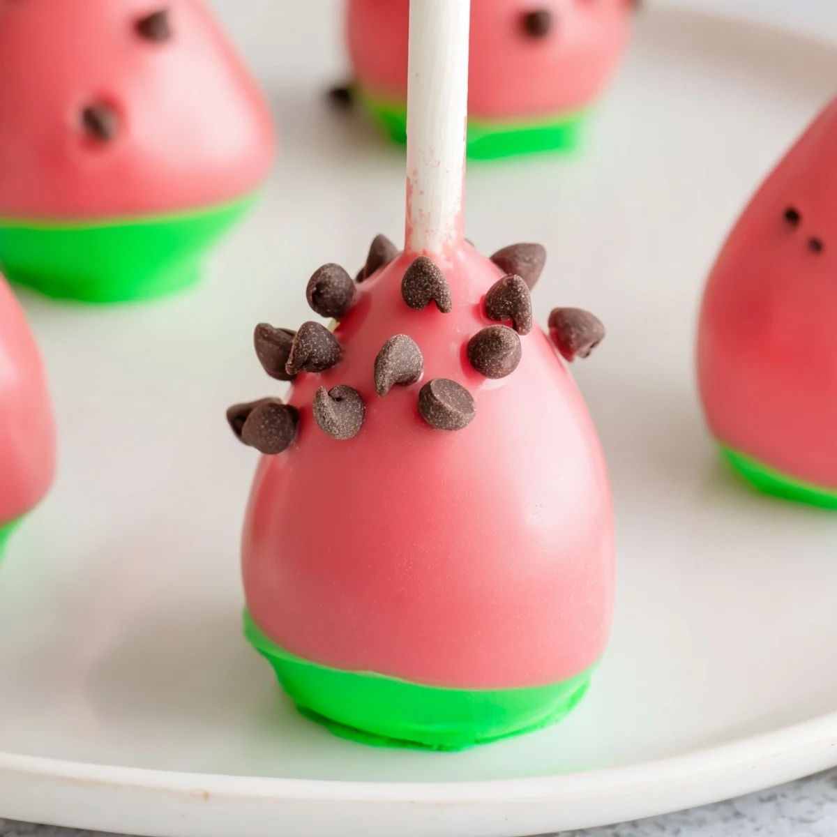Summer dessert table featuring watermelon cake pops on sticks with red and green layers