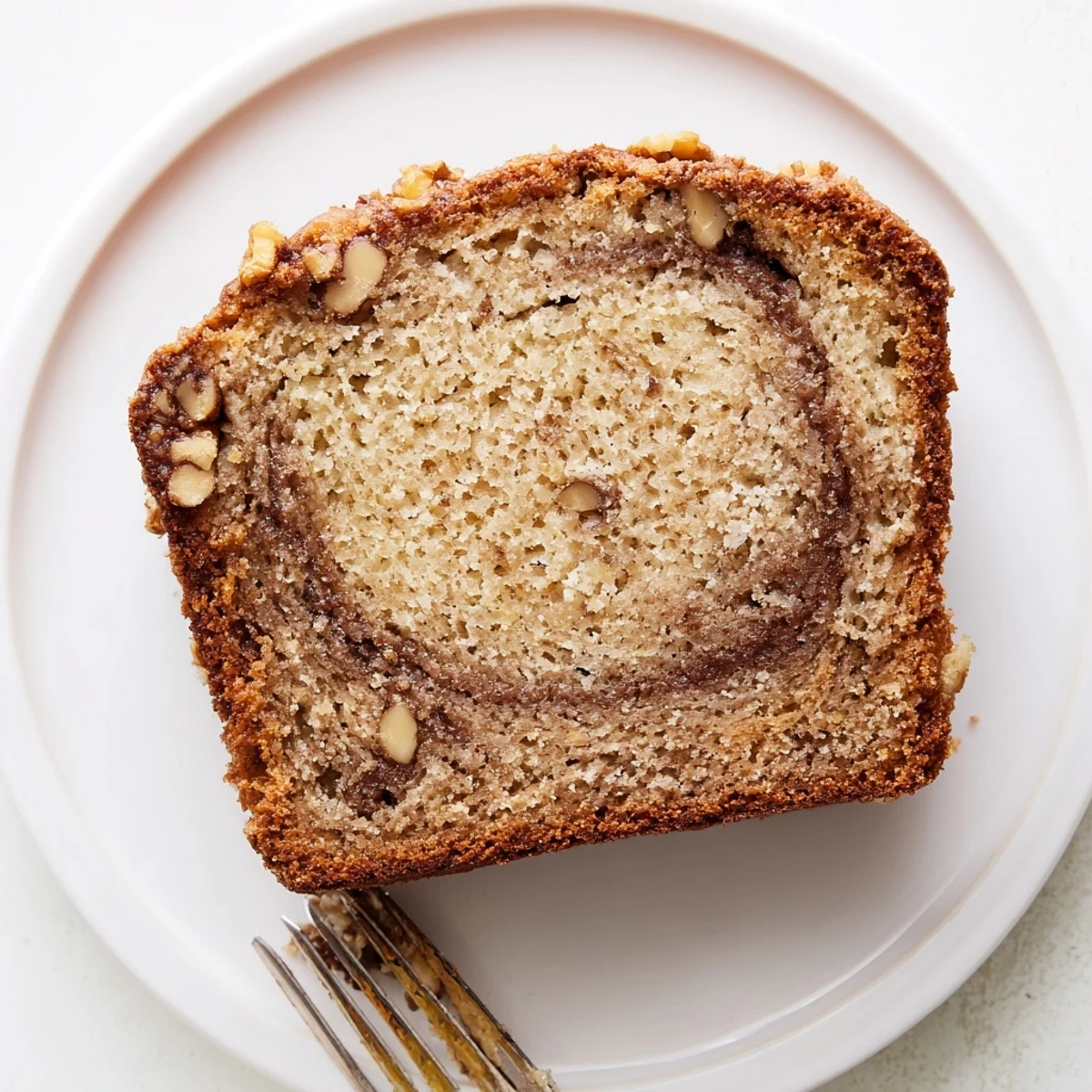 Golden brown banana nut bread loaf with walnuts and cinnamon sugar swirl marbled throughout