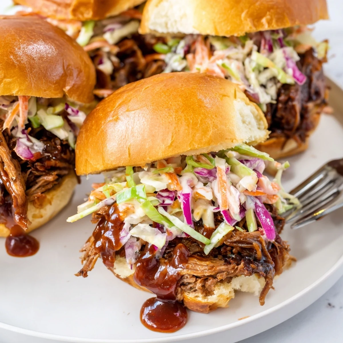 Tender smoky beef sliders topped with fresh coleslaw on golden brioche buns
