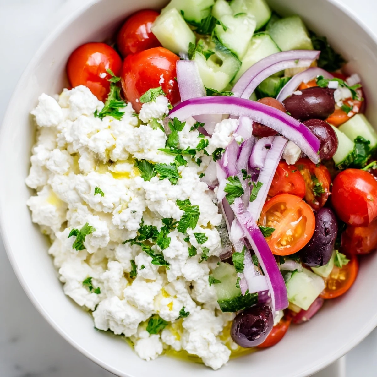 Creamy cottage cheese bowl topped with crisp vegetables, olives, and feta in a Greek-inspired salad
