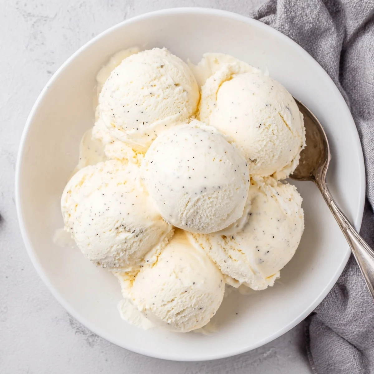 Rich vanilla bean ice cream recipe garnished with wafer cookies on a rustic wooden serving board
