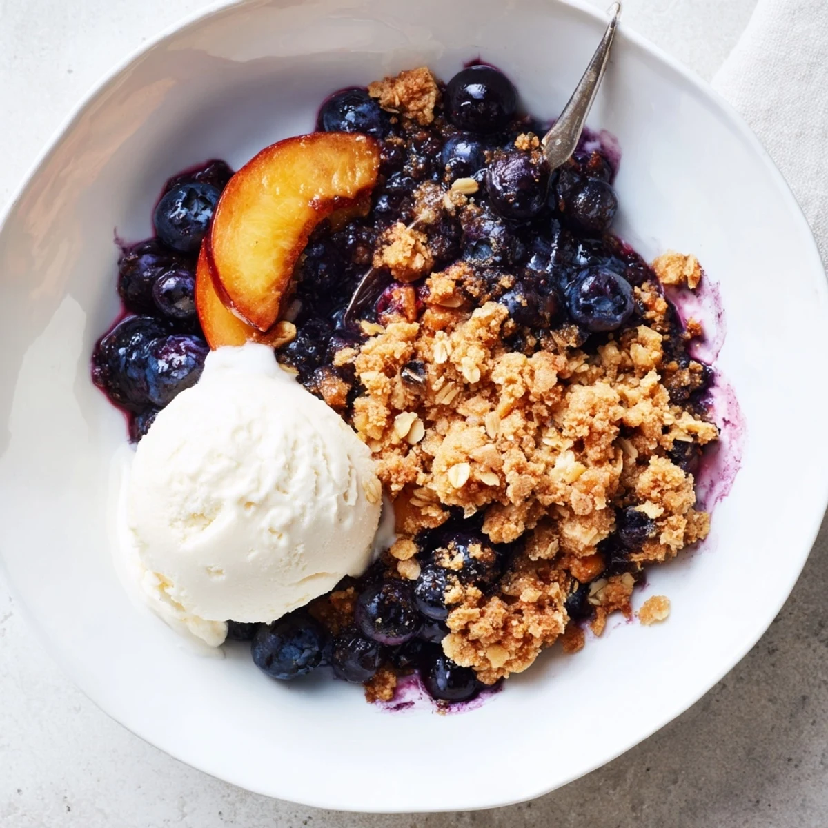 Warm Blueberry Peach Crumble served with melting vanilla ice cream and cinnamon