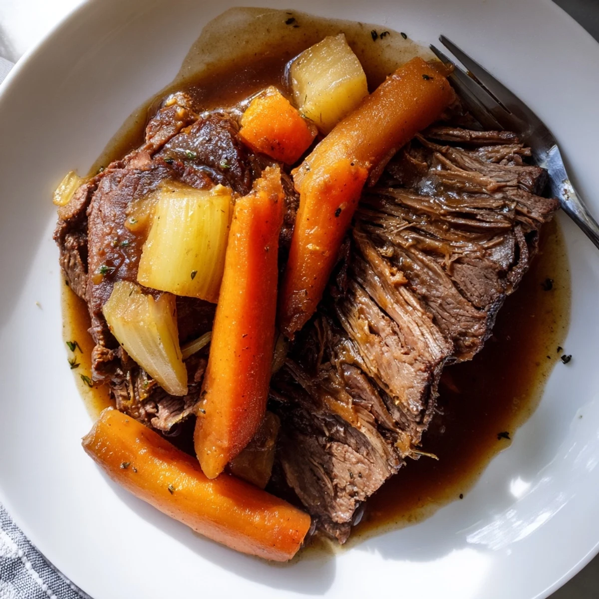 Tender perfect pot roast surrounded by glazed carrots and rich brown gravy