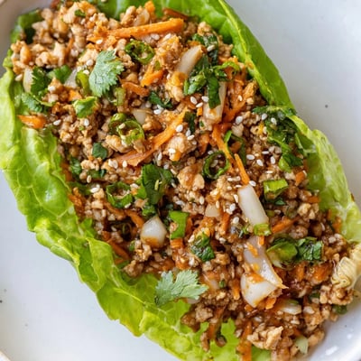 A close-up shows vibrant carrots and water chestnuts mixed into the savory chicken filling, served as an easy Potsticker Chicken Lettuce Boats meal.  
