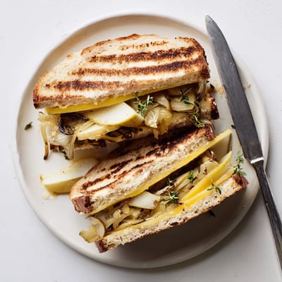 A close-up of a sliced Pear, Apple & Grilled Cheese with Caramelized Onions, showing gooey cheese and fruit.