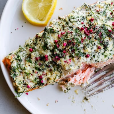 Boursin salmon topped with melted garlic herb cheese served on a white plate